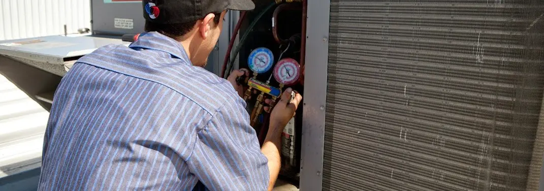 HVAC technician servicing a condenser unit in West Memphis